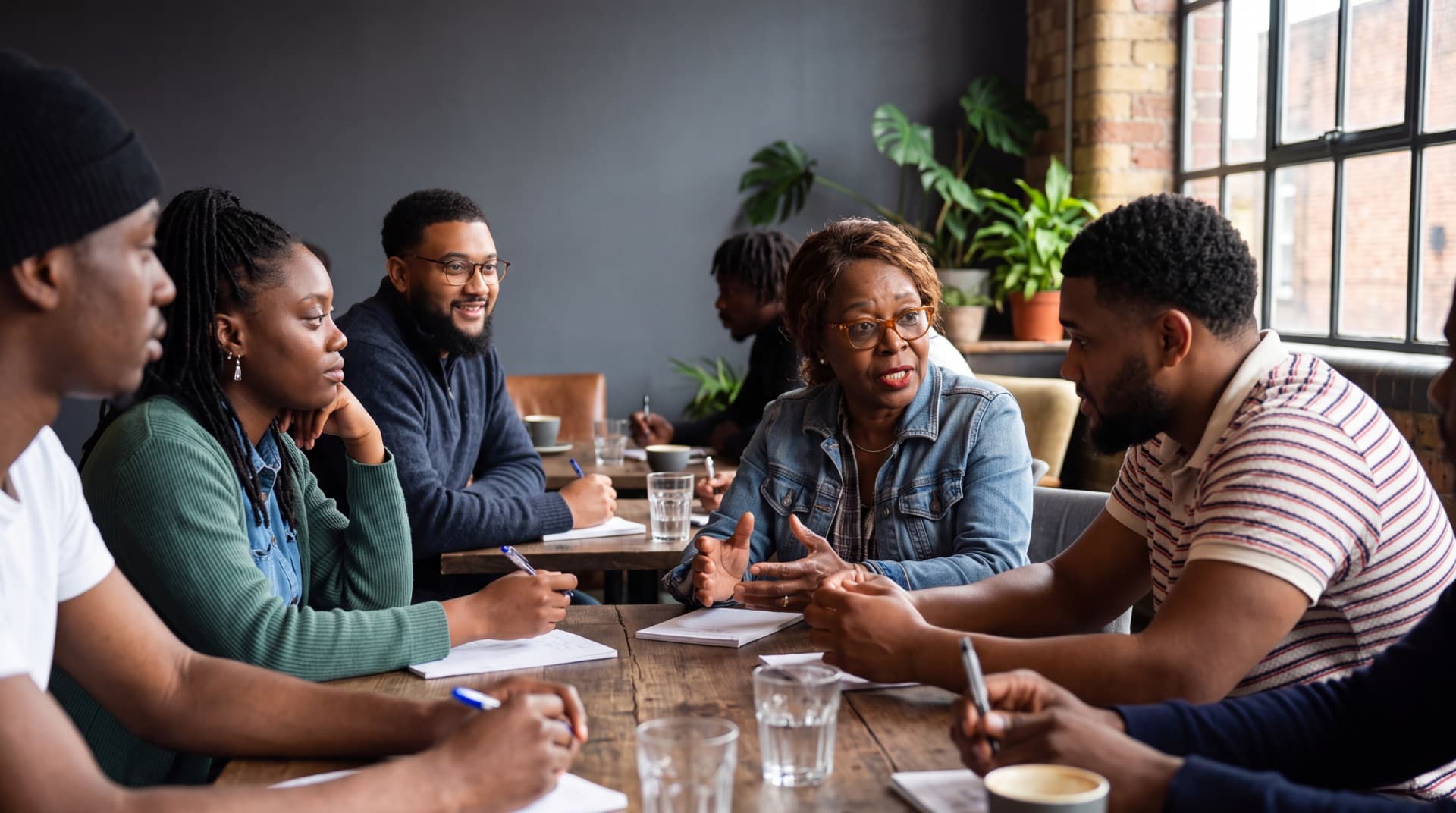 A community conversation in progress, with residents and researchers taking notes around a table
